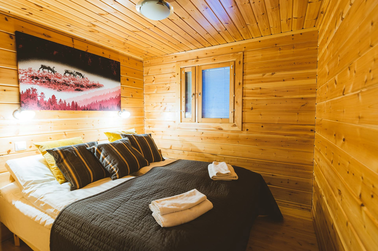 Viihtyis&auml; makuuhuone hirsim&ouml;kiss&auml; Lapissa, parivuode ja puinen sisustus